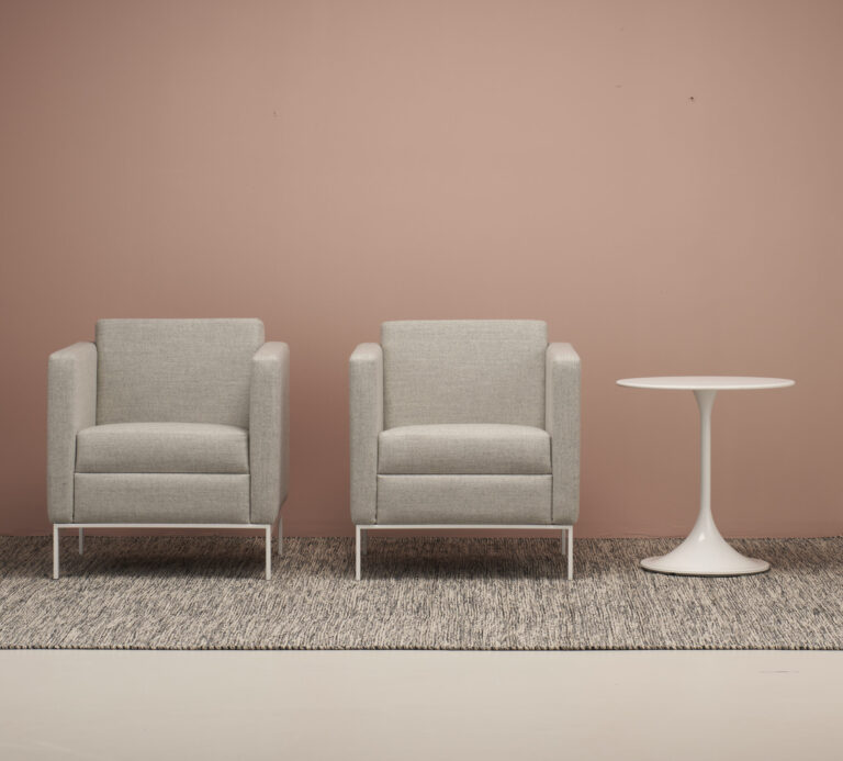 Two Cumberland lounge chairs and side table in front of a pink wall.