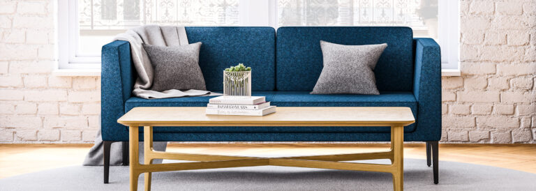 A blue JSI Arwyn sofa in a bright room in front of a large window.