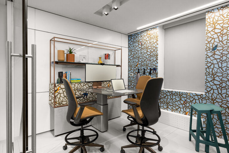 A conference room with three chairs around a small table and a wallcovering with a vine pattern.