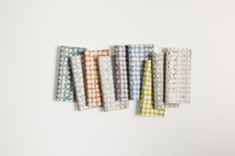 A row of various colored textiles that have a circle-on-circle pattern on a white background.