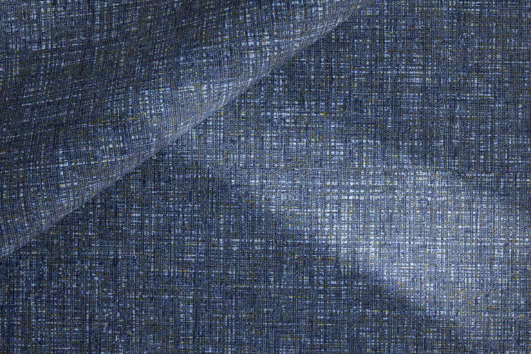 A blue-coated textile that is rolled on top of itself, where the delicate, multi-layered colors are visible.