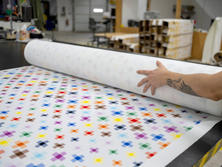 Image of colorful fabric being rolled onto a table